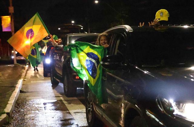 Supporters of Brazil's right-wing presidential candidate Flavio Bolsonaro celebrate the partial results of the presidential election in Porto Alegre, Brazil, on October 4, 2026. Brazilian right-wing presidential candidate Flavio Bolsonaro maintained a strong lead over President Luiz Inacio Lula da Silva with presidential election results from over 60 percent of electronic ballot boxes counted. (Photo by SILVIO AVILA / AFP)