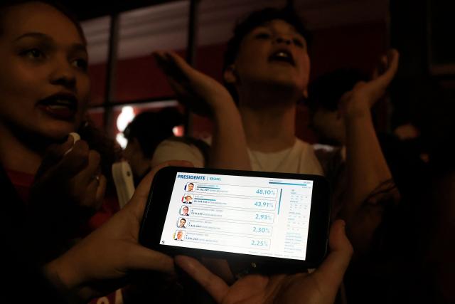 A person checks their cellphone following the partial results of the presidential election in Sao Paulo, Brazil on October 4, 2026. Brazilian senator Flavio Bolsonaro, son of the far-right former president Jair Bolsonaro, is leading incumbent Luiz Inacio Lula da Silva in partial results from October 4, 2026, election. (Photo by Miguel SCHINCARIOL / AFP)