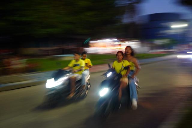 People ride motorbikes following the partial results of the presidential election in Tabatinga, Amazonas state, Brazil, on October 4, 2026. Brazilian senator Flavio Bolsonaro, son of the far-right former president Jair Bolsonaro, is leading incumbent Luiz Inacio Lula da Silva in partial results from October 4, 2026, election. (Photo by Pablo VERA / AFP)