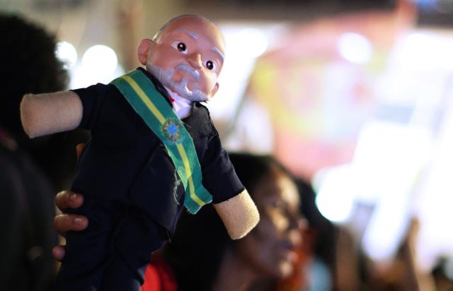 A supporter of Brazil's President and Presidential candidate Luiz Inacio Lula da Silva holds a toy depicting him following the results of the presidential election in Brasilia on October 4, 2026. Brazilian senator Flavio Bolsonaro, son of the far-right former leader Jair Bolsonaro, finished ahead of President Luiz Inacio Lula da Silva in the election on October 4, 2026, which will go to a run-off in three weeks. (Photo by Igo Estrela / AFP)