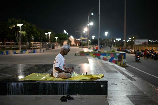 A man meditates while practising yoga early morning at the Marina beach in Chennai on October 5, 2026. (Photo by R. Satish BABU / AFP)