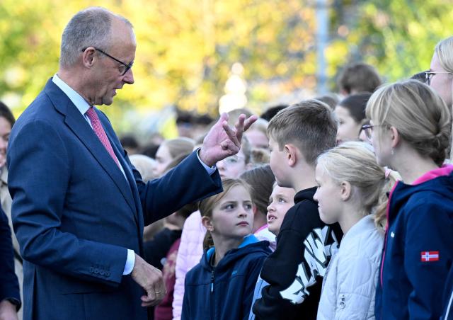 German Chancellor Friedrich Merz talks with young students as he arrives for a visit at his former secondary school, the Friedrich-Spee-Gymnasium in Ruethen, western Germany, on October 5, 2026, as the school is celebrating its 100th anniversary. (Photo by INA FASSBENDER / AFP)