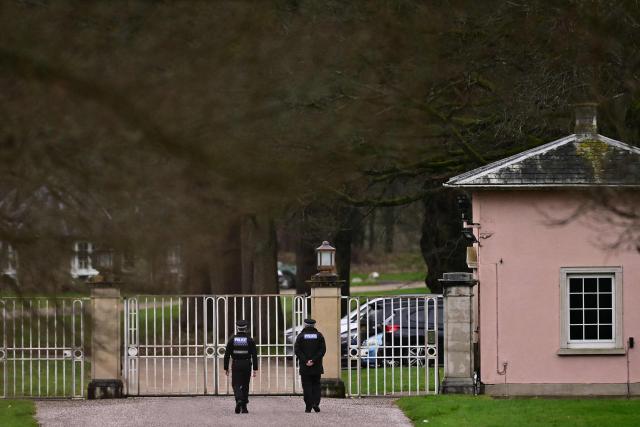 (FILES) Police officers walk towards the entrance to Royal Lodge, a 30-room property and former residence to Britain's former prince Andrew where police said they are still conducting a search, in Windsor, west of London on February 20, 2026, a day after Andrew Mountbatten-Windsor was arrested on the royal family's remote Sandringham estate in eastern England. Disgraced ex-prince Andrew Mountbatten-Windsor has launched a legal challenge over search warrants for his royal estate homes issued before his February arrest, Britain's judiciary confirmed Monday, October 5, in an unprecedented royal move in modern times. (Photo by Ben STANSALL / AFP)