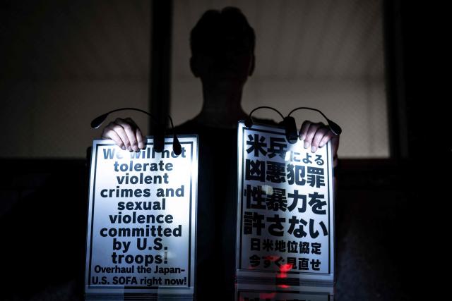 A man holds placards reading 'We will not tolerate violent crimes and sexual violence commited by US troops' during a protest against the killing of a woman in Okinawa allegedly committed by a US Marine Corps member, in front of the Prime Minister's Office in Tokyo on October 5, 2026. A woman's murder allegedly committed by a US Marine in Okinawa is a "heinous crime", Japan's premier said on October 5, as the new accusation of violence involving American forces sparked public outrage. (Photo by Yuichi YAMAZAKI / AFP)