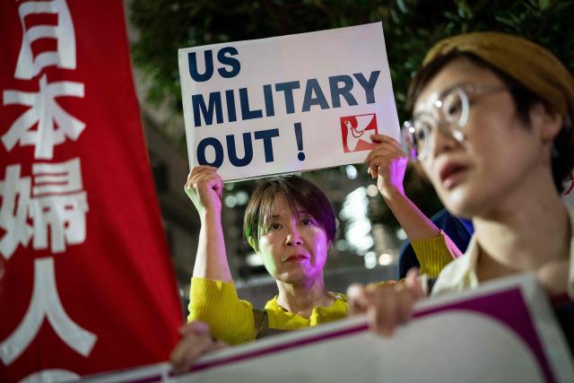 A woman holds up a placard reading 'US military out' during a protest against the killing of a woman in Okinawa allegedly committed by a US Marine Corps member, in front of the Prime Minister's Office in Tokyo on October 5, 2026. A woman's murder allegedly committed by a US Marine in Okinawa is a "heinous crime", Japan's premier said on October 5, as the new accusation of violence involving American forces sparked public outrage. (Photo by Yuichi YAMAZAKI / AFP)