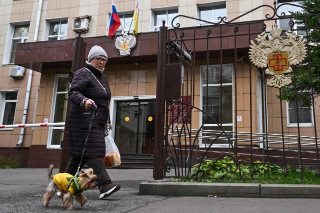 A woman walks a dog past the headquarters of Russia's consumer and health watchdog Rospotrebnadzor in Moscow on October 5, 2026. Russian officials on October 5, 2026 downplayed reports that a laboratory technician in Siberia had died of plague, insisting the situation was under control and that post-mortem tests had not found traces of the disease. (Photo by Igor IVANKO / AFP)