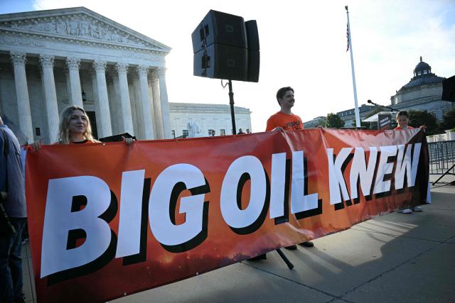 People hold a banner as they arrive to protest outside the US Supreme Court as the court considers the Suncor v. Boulder case in Washington, DC, on October 5, 2026. The US Supreme Court hears a climate case that could upend dozens of lawsuits aimed at making polluters pay for their role in global warming and allegedly deceiving the public about the dangers of fossil fuels. (Photo by Jim WATSON / AFP)