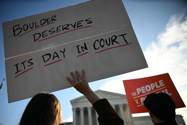 People hold signs as they protest in front of the US Supreme Court as the court considers the Suncor v. Boulder case in Washington, DC, on October 5, 2026. The US Supreme Court hears a climate case that could upend dozens of lawsuits aimed at making polluters pay for their role in global warming and allegedly deceiving the public about the dangers of fossil fuels. (Photo by Jim WATSON / AFP)