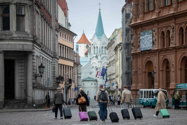 This photograph taken on October 4, 2026 shows a a group of tourists pulling their suitcases across the Cathedral Square (Doma laukums) in Riga, Latvia. (Photo by Wojtek RADWANSKI / AFP)