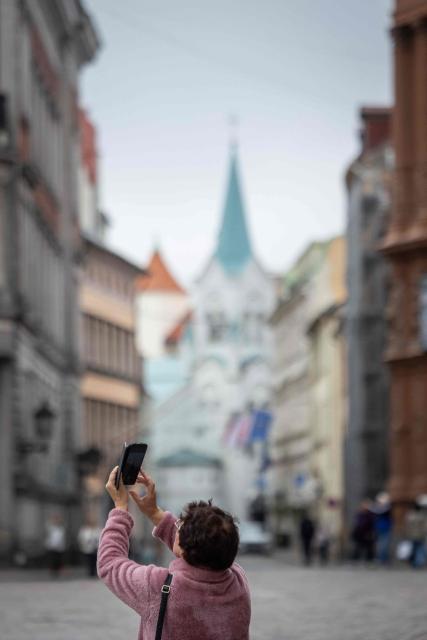 This photograph taken on October 4, 2026 shows  a tourist taking a picture of the Cathedral Square (Doma laukums) in Riga, Latvia. (Photo by Wojtek RADWANSKI / AFP)