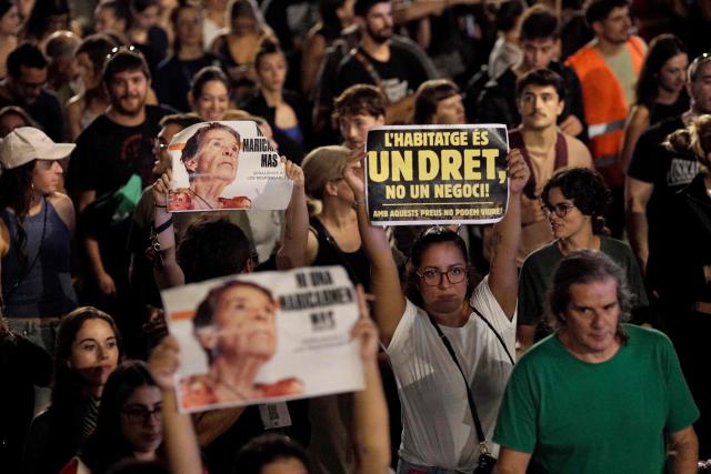 Demonstrators hold signs reading 'Housing is a right not a business' and 'Not a single more Maricarmen' in a reference to an 87-year-old evicted from her Madrid home, during a protest against evictions and high rent prices on plaza Tetuan in Barcelona on October 5, 2026. Spain's Socialist Prime Minister on October 5, 2026 called a snap election for November 29, after parliament rejected housing relief measures proposed by his minority government amid nationwide protests against evictions and high rent prices. (Photo by Manaure Quintero / AFP)