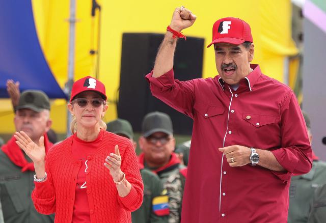 (FILES) Venezuelan President Nicolas Maduro raises his fist next to his wife Cilia Flores during a rally to commemorate the 33rd anniversary of late President Hugo Chavez's 1992 failed military coup against the government (1989-1993) of Carlos Andres Perez in Caracas on February 4, 2025. Ousted former Venezuelan president Nicolas Maduro's jailed wife Cilia Flores has a "very delicate" heart condition requiring surgery, Maduro's son told AFP on October 5, 2026, after Flores requested to be released on house arrest. (Photo by Pedro MATTEY / AFP)