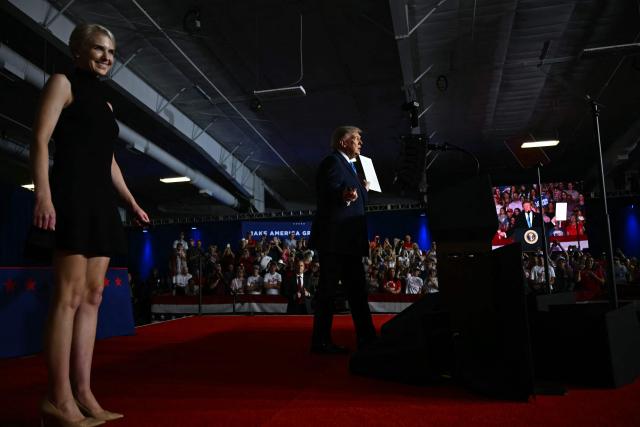 Executive assistant to US President Donald Trump, Natalie Harp, stands on stage with US President Donald Trump as he holds up an executive order during a campaign rally at Pinnacle Bank Expo Center in Grand Island, Nebraska, on October 5, 2026. (Photo by Kent NISHIMURA / AFP)