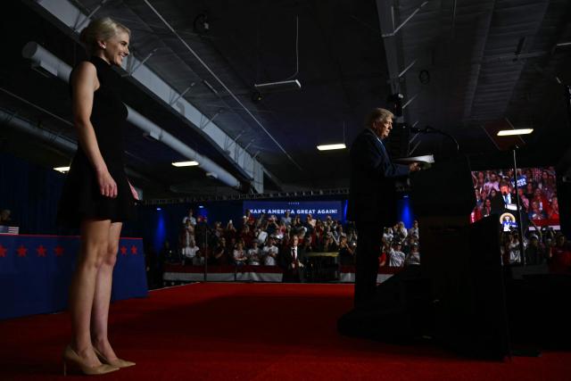Executive assistant to US President Donald Trump, Natalie Harp, stands on stage with US President Donald Trump as he reads an executive order during a campaign rally at Pinnacle Bank Expo Center in Grand Island, Nebraska, on October 5, 2026. (Photo by Kent NISHIMURA / AFP)