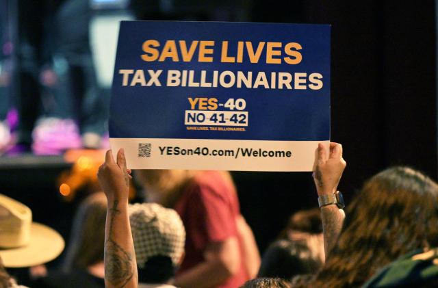 An audience member holds up a sign during a California Wealth Tax rally in Los Angeles on October 5, 2026. (Photo by Frederic J. BROWN / AFP)