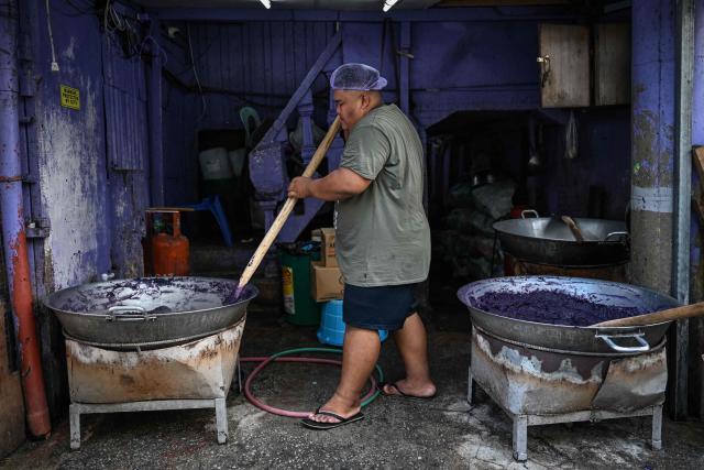 This photo taken on October 1, 2026 shows a worker making purple yam jam (ube halaya) at a shop in Manila. The Philippine ube has become a trend-setting sensation from Los Angeles to London to Seoul, with the humble yam's bright purple hue drawing lines outside coffee shops and bakeries and millions of views on social media. But keeping pace with the international boom has proven tricky for the archipelago nation's overwhelmingly smallholder farmers, with yields declining and some unable to commit to the plant's nine-month growing time. (Photo by Jam STA ROSA / AFP) / To go with AFP story Philippines-lifestyle-food-drink-ube, FOCUS by Cecil Morella and Atish Patel