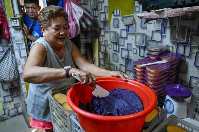 This photo taken on October 1, 2026 shows a worker preparing purple yam jam (ube halaya) at a shop in Manila. The Philippine ube has become a trend-setting sensation from Los Angeles to London to Seoul, with the humble yam's bright purple hue drawing lines outside coffee shops and bakeries and millions of views on social media. But keeping pace with the international boom has proven tricky for the archipelago nation's overwhelmingly smallholder farmers, with yields declining and some unable to commit to the plant's nine-month growing time. (Photo by Jam STA ROSA / AFP) / To go with AFP story Philippines-lifestyle-food-drink-ube, FOCUS by Cecil Morella and Atish Patel