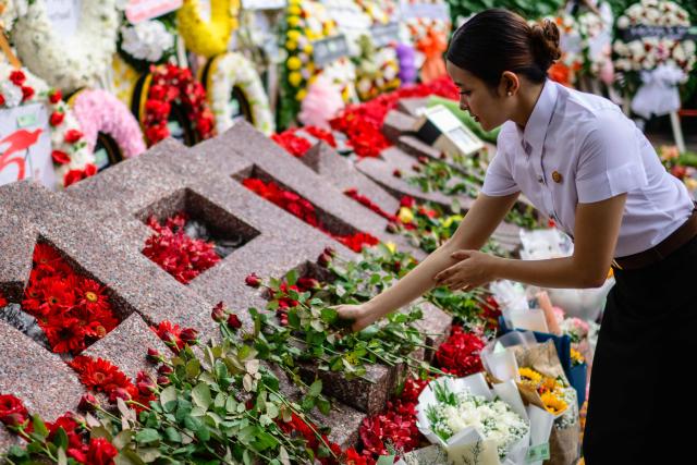 A woman places a flower on a monument to mark the 50th anniversary of the Thammasat University massacre on October 6, 1976, during the annual commemoration ceremony for the event at Thammasat University in Bangkok on October 6, 2026. (Photo by ANTHONY WALLACE / AFP)