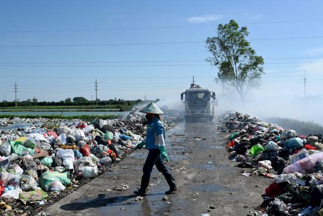 A woman walks through a landfill site on the outskirts of Hanoi on October 6, 2026. (Photo by Nhac NGUYEN / AFP)