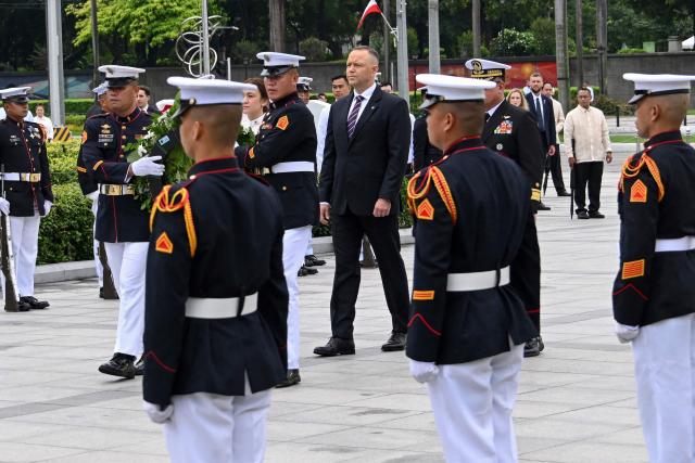 Poland's President Karol Nawrocki (R) takes part in a wreath-laying ceremony at the Rizal Monument in Manila on October 6, 2026. (Photo by Ted ALJIBE / AFP)