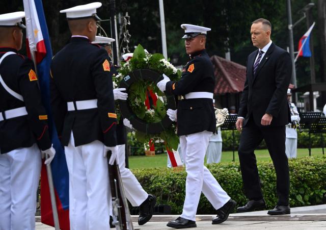 Poland's President Karol Nawrocki (R) takes part in a wreath-laying ceremony at the Rizal Monument in Manila on October 6, 2026. (Photo by Ted ALJIBE / AFP)