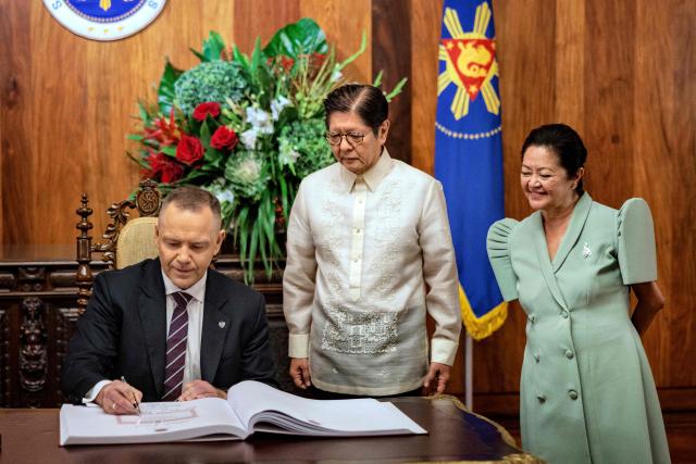 Polish President Karol Nawrocki (L) signs a guestbook as Philippines' President Ferdinand Marcos Jr (C) and his wife Louise Araneta Marcos look on at Malacanang Palace in Manila on October 6, 2026. (Photo by Ezra Acayan / POOL / AFP)
