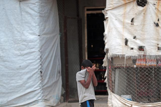 A boy pulls up his t-shirt while walking through the Roj detention camp built for relatives of suspected jihadists, in the northeast of Syria on October 5, 2026. (Photo by Delil SOULEIMAN / AFP)