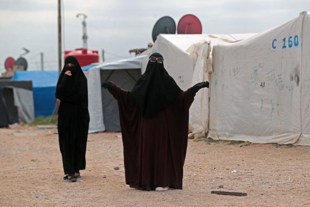 A woman gestures while standing outside her tent at the Roj detention camp built for relatives of suspected jihadists, in the northeast of Syria on October 5, 2026. (Photo by Delil SOULEIMAN / AFP)
