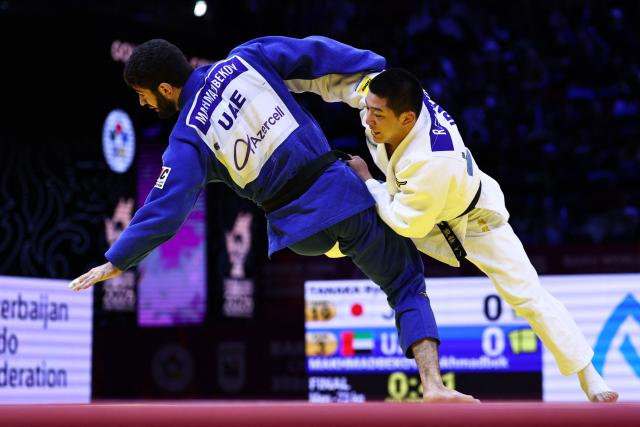 Japan's Ryuga Tanaka (white) competes against United Arab Emirates' Makhmadbek Makhmadbekov in the men's under 73 kg category gold medal bout at the World Judo Championships in Baku on October 6, 2026. (Photo by Anne-Christine POUJOULAT / AFP)