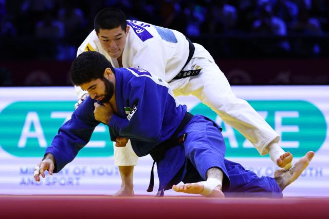 Japan's Ryuga Tanaka (white) competes against United Arab Emirates' Makhmadbek Makhmadbekov in the men's under 73 kg category gold medal bout at the World Judo Championships in Baku on October 6, 2026. (Photo by Anne-Christine POUJOULAT / AFP)