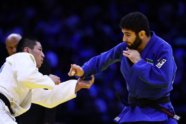 Japan's Ryuga Tanaka (white) competes against United Arab Emirates' Makhmadbek Makhmadbekov in the men's under 73 kg category gold medal bout at the World Judo Championships in Baku on October 6, 2026. (Photo by Anne-Christine POUJOULAT / AFP)