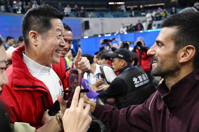 Serbia's Novak Djokovic (R) signs a fan's shirt after winning the men's singles final at the China Open tennis tournament in Beijing on October 6, 2026. (Photo by GREG BAKER / AFP)
