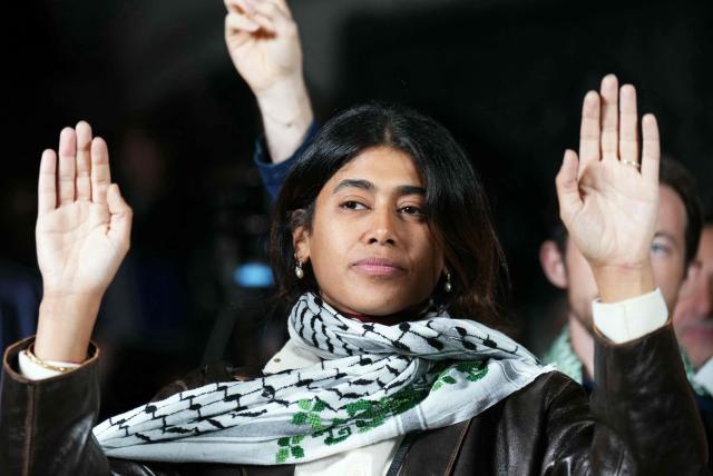 (FILES) French-Palestinian lawyer and member of European Parliament for La France Insoumise (LFI) party Rima Hassan (C) takes part in a gathering organised by activists who had sailed aboard vessels from the Gaza-bound aid flotilla before being stopped and detained by Israeli forces, at the Place de la Republique in Paris, on October 8, 2025. If the allegations that MEP Rima Hassan knocked over Israeli and European flags during an exhibition dedicated to the attacks of 7 October 2023 were to be proven true, they “would call for exemplary sanctions from the European Parliament”, the French Foreign Minister said on October 6, 2026. “I hope that the commemorations can take place under the best possible conditions, whilst remembering that 51 of our compatriots lost their lives” in that tragedy, Jean-Noлl Barrot told the National Assembly. (Photo by Dimitar DILKOFF / AFP)
