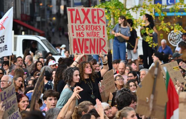 A person holds up a placard reading in French "Tax the rich, not our futur" during a demonstration part of a nationwide day of actions called by high-school students, joined by unions and teachers, who for days have been demanding better learning conditions in protests punctuated by violent confrontations in Bayonne, southwestern France, on October 6, 2026. Students have blocked the entrances to hundreds of high schools for 15- to 17-year-olds since late September, complaining of missing teachers, overloaded timetables, dilapidated classrooms and buildings that cannot cope with rising temperatures. (Photo by Gaizka IROZ / AFP)