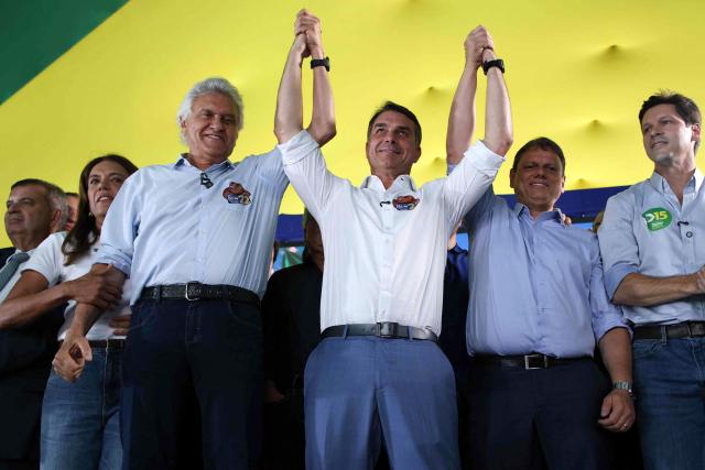 Brazil's right-wing senator and Liberal Party (PL) presidential candidate Flavio Bolsonaro (C) raises hands with former presidential candidate Ronaldo Caiado (L) and Sao Paulo Governor Tarcisio de Freitas during a rally in Goiania, Goias state, Brazil, on October 6, 2026. Right-wing Flavio Bolsonaro heads into Brazil's October 25 presidential runoff in a position of strength and with the backing of US President Donald Trump, while President Luiz Inacio Lula da Silva faces an uphill battle to stage a comeback. (Photo by Sergio LIMA / AFP)