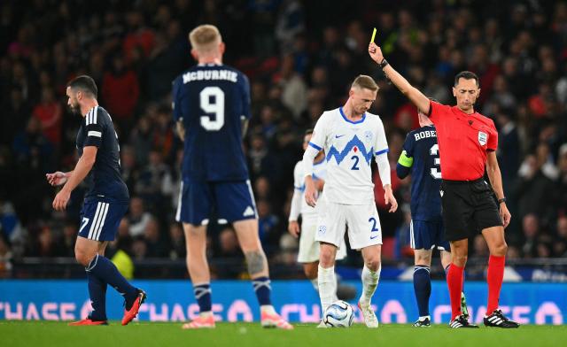 Spanish referee Jose Maria Sanchez Santos shows a yellow card to Scotland's midfielder #07 John McGinn (L) during the UEFA Nations League, League B, Group 1 football match between Scotland and Slovenia at Hampden Park in Glasgow, Scotland on October 6, 2026.  (Photo by ANDY BUCHANAN / AFP)