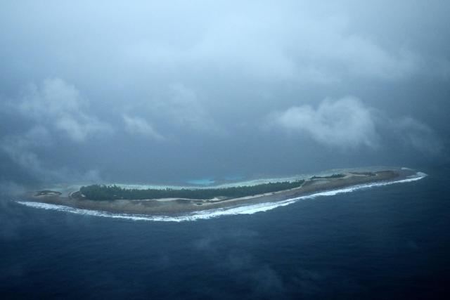 This picture taken on October 6, 2026 shows an aerial view of an island of Tuvalu on a cloudy day. The low-lying Pacific island nation is widely regarded as one of the countries most vulnerable to climate change and rising sea levels, which threaten its land, infrastructure and freshwater resources. (Photo by Saeed KHAN / AFP)