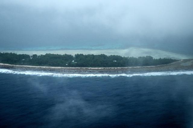 This picture taken on October 6, 2026 shows an aerial view of an island of Tuvalu on a cloudy day. The low-lying Pacific island nation is widely regarded as one of the countries most vulnerable to climate change and rising sea levels, which threaten its land, infrastructure and freshwater resources. (Photo by Saeed KHAN / AFP)