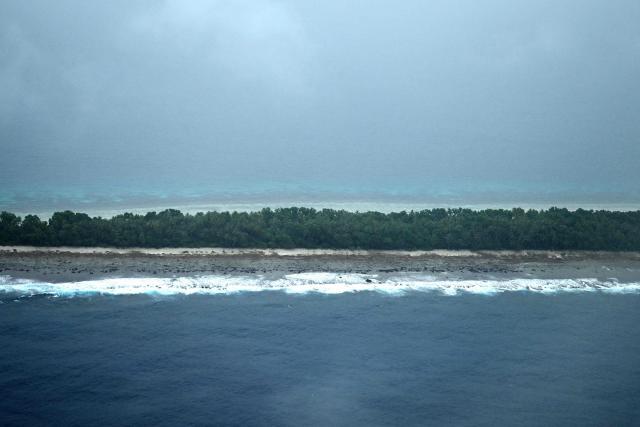 This picture taken on October 6, 2026 shows an aerial view of an island of Tuvalu on a cloudy day. The low-lying Pacific island nation is widely regarded as one of the countries most vulnerable to climate change and rising sea levels, which threaten its land, infrastructure and freshwater resources. (Photo by Saeed KHAN / AFP)