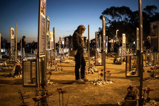A mourner pays respect at the site of the Nova music festival in Re'im, southern Israel on October 7, 2026, to mark the third anniversary of Hamas's October 7, 2023 attack. Mourners observed a moment of silence on October 7 at sites in southern Israel attacked by Hamas three years earlier, the country's deadliest ever attack which triggered a massive Israeli offensive in Gaza. At the site of the Nova music festival, which Hamas militants infiltrated on October 7, 2023 through cars and paragliders, family members bowed their heads at 6:29 am (0329 GMT), surrounded by portraits of victims with flowers placed underneath. (Photo by JOHN WESSELS / AFP)