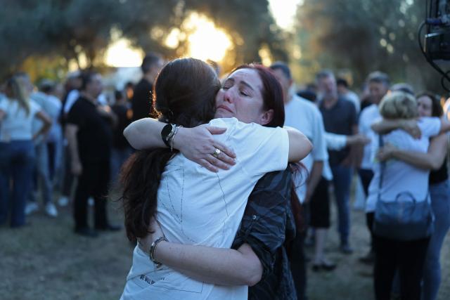 Israelis embrace each other while attending a tribute ceremony at the Kibbutz Kfar Aza, in southern Israel on October 7, 2026. Israel marks the third anniversary of Hamas's October 7, 2023 attack, just weeks before an election in which the deadliest day in the country's history will be front and centre. At 06:29 am (0329 GMT), the exact time the Hamas attack began three years ago, a tribute was held at Kibbutz Kfar Aza near the Gaza border, where militants killed 64 residents and abducted 18 people during their attack. (Photo by Ilia YEFIMOVICH / AFP)