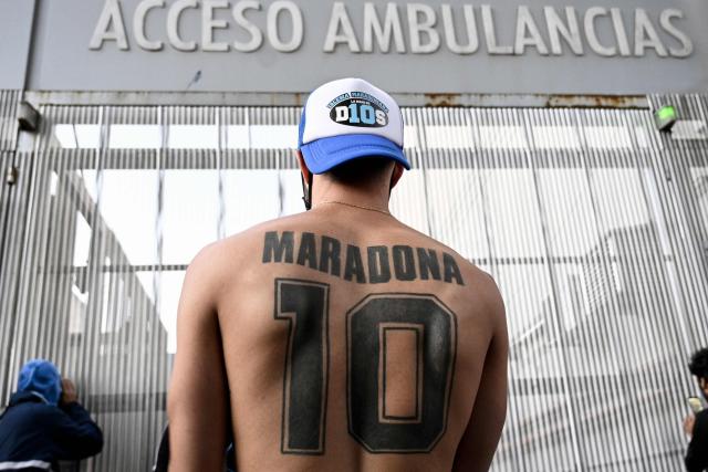 (FILES) A supporter of Argentine former football star and coach of Gimnasia y Esgrima La Plata Diego Maradona displays his tattoo, outside the hospital where he will undergo brain surgery for a blood clot, in Olivos, Buenos Aires province, on November 3, 2020. The trial over Diego Maradona's death enters its final stage in early October 2026 after almost six months of hearings, with the question still unresolved as to whether the football icon's death in late 2020 was unforeseeable or the result of medical negligence during his home care. (Photo by JUAN MABROMATA / AFP)