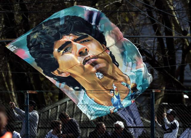 (FILES) Supporters of Gimnasia y Esgrima La Plata cheer for their team and its new coach, Argentine former football star Diego Armando Maradona, before the start of their Argentina First Division Superliga football match against Racing Club, at El Bosque stadium, in La Plata, Buenos Aires province, Argentina, on September 15, 2019. The trial over Diego Maradona's death enters its final stage in early October 2026 after almost six months of hearings, with the question still unresolved as to whether the football icon's death in late 2020 was unforeseeable or the result of medical negligence during his home care. (Photo by ALEJANDRO PAGNI / AFP)
