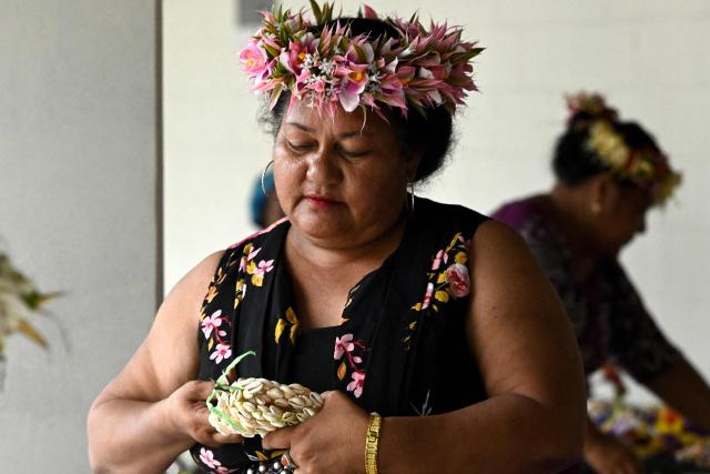 This photo taken on October 6, 2026 shows a traditionally-dressed Tuvaluan woman preparing souvenirs for visitors outside Funafuti International Airport, Tuvalu, during the Pacific Pre-COP31 Summit. Tuvalu, one of the world's most climate-vulnerable nations, is hosting regional discussions on climate change and rising sea levels ahead of the UN COP31 conference. (Photo by Saeed KHAN / POOL / AFP)