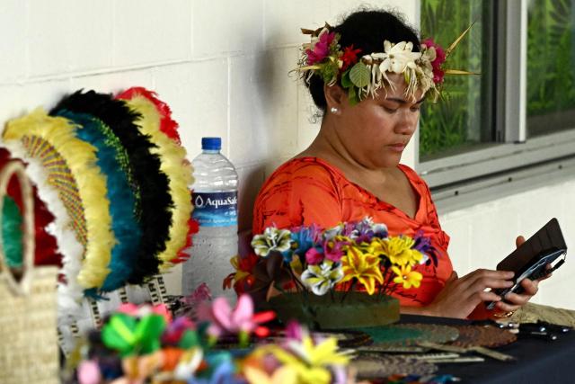 This photo taken on October 6, 2026 shows a traditionally-dressed Tuvaluan selling souvenirs outside Funafuti International Airport, Tuvalu, during the Pacific Pre-COP31 Summit. Tuvalu, one of the world's most climate-vulnerable nations, is hosting regional discussions on climate change and rising sea levels ahead of the UN COP31 conference. (Photo by Saeed KHAN / POOL / AFP)
