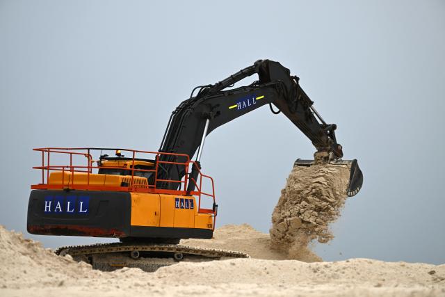 This photo taken on October 6, 2026 shows a heavy earthmoving machinery depositing sand at a land reclamation site in Funafuti, Tuvalu. Tuvalu is expanding adaptation measures, including land reclamation and coastal protection works, as rising sea levels linked to climate change threaten the future of the low-lying Pacific island nation. (Photo by Saeed KHAN / POOL / AFP)