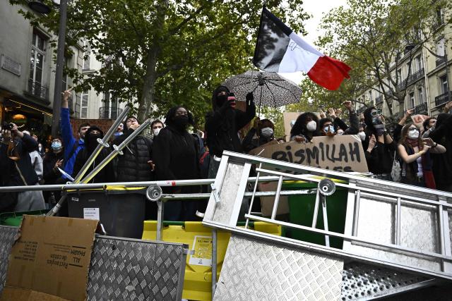 Protesters including one with a French flag take part in a street blockade during a demonstration in solidarity with high-school students near Sciences Politiques (Paris Institute of Political Studies) university as part of a nationwide protest movement over learning conditions in Paris, on October 7, 2026. Since late September, pupils have barred the entrances to hundreds of schools, complaining of teacher absences, overloaded timetables, dilapidated classrooms and buildings ill-adapted to rising temperatures, among other grievances. (Photo by JULIEN DE ROSA / AFP)