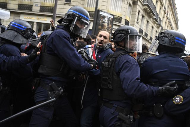 French police in riot gear push La France Insoumise - Nouveau Front Populaire's MP Thomas Portes during a demonstration in solidarity with high-school students near Sciences Politiques (Paris Institute of Political Studies) university as part of a nationwide protest movement over learning conditions in Paris, on October 7, 2026. Since late September, pupils have barred the entrances to hundreds of schools, complaining of teacher absences, overloaded timetables, dilapidated classrooms and buildings ill-adapted to rising temperatures, among other grievances. (Photo by JULIEN DE ROSA / AFP)