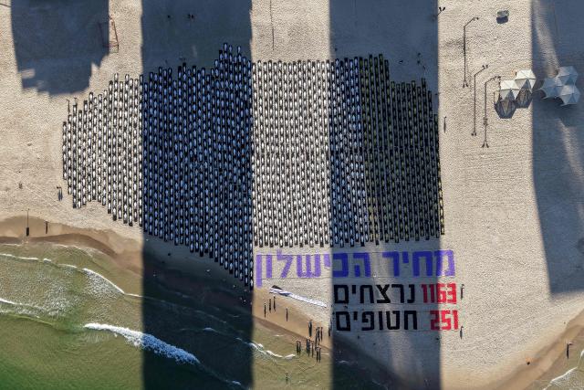 An aerial view shows people standing on the beach next to a commemorative installation marking the third anniversary of Hamas's October 7 attack on Israel, in Tel Aviv on October 7, 2026. Israel marked the third anniversary of Hamas's October 7 attack with silent tributes, new strikes on Gaza and intense political debate, weeks before elections in which the country's deadliest day will be front and centre. (Photo by Jack GUEZ / AFP)