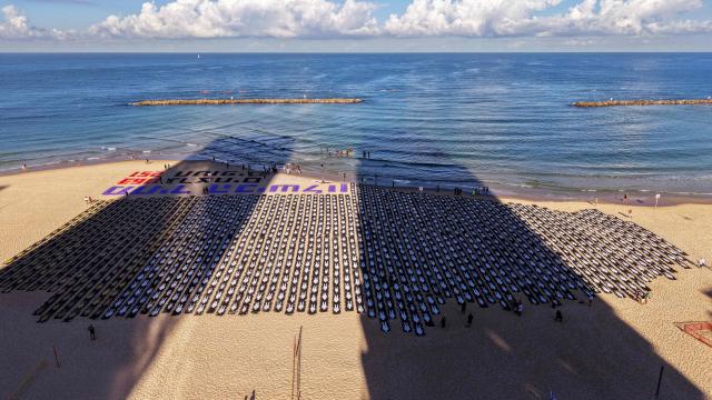 An aerial view shows people standing on the beach next to a commemorative installation marking the third anniversary of Hamas's October 7 attack on Israel, in Tel Aviv on October 7, 2026. Israel marked the third anniversary of Hamas's October 7 attack with silent tributes, new strikes on Gaza and intense political debate, weeks before elections in which the country's deadliest day will be front and centre. (Photo by Jack GUEZ / AFP)